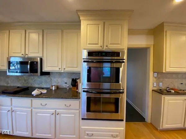 a kitchen with granite countertop white cabinets and stainless steel appliances
