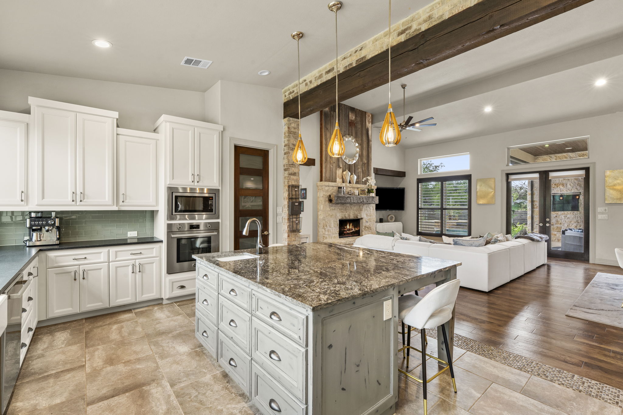 16202 Remuda Trail Buda, TX 78610 - Photo 9 of 40 This open-concept living area features a kitchen with white cabinetry, stainless steel appliances, and an expansive island with a sink and seating
