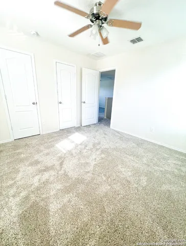 an empty room with a ceiling fan and window