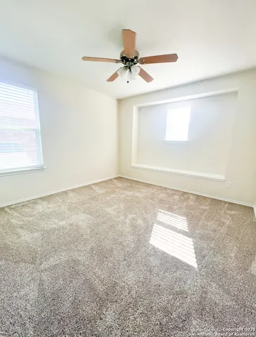an empty room with a ceiling fan and window