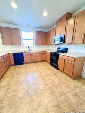 a large kitchen with stainless steel appliances granite countertop a stove a sink dishwasher and wooden cabinets