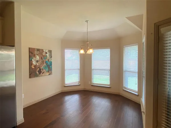 a view of an empty room with wooden floor and fan