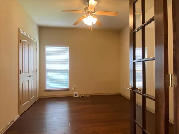 an empty room with wooden floor fan and windows