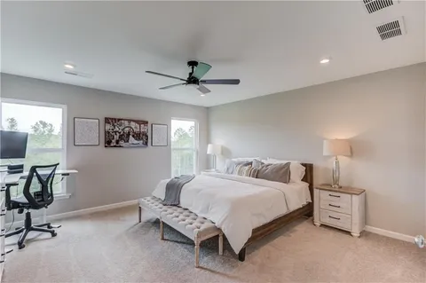 a spacious bedroom with a bed a desk and chair