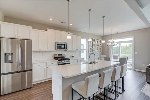 a kitchen with stainless steel appliances granite countertop a stove a refrigerator a kitchen island a sink cabinets and a refrigerator