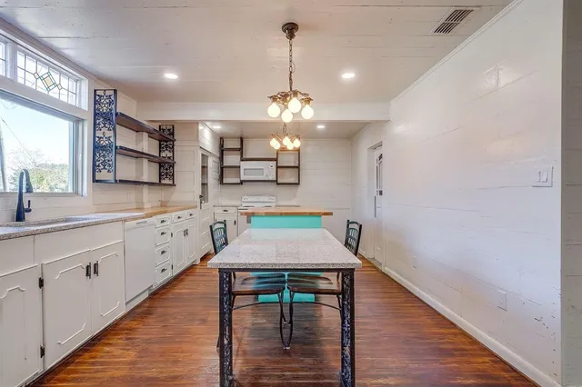 a room with kitchen island a chandelier and wooden floor