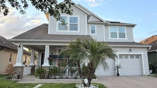 front view of house with a yard and palm trees