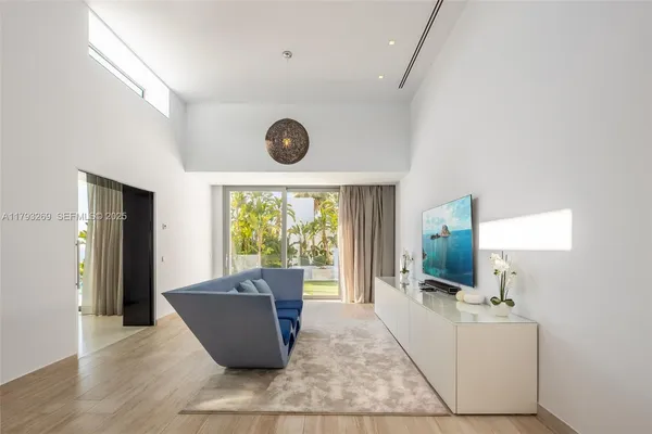 a living room with furniture a flat screen tv and a floor to ceiling window