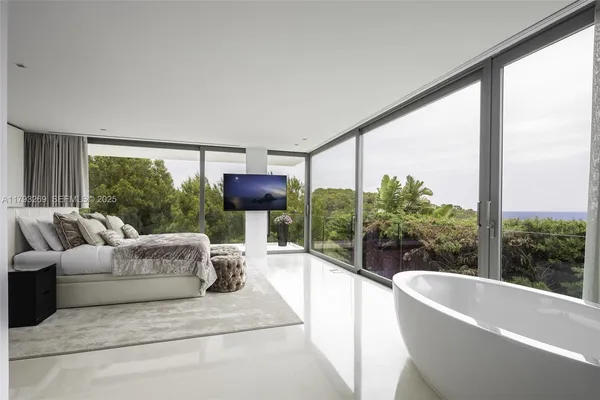 a bedroom with a bed and a flat tv screen next to a window