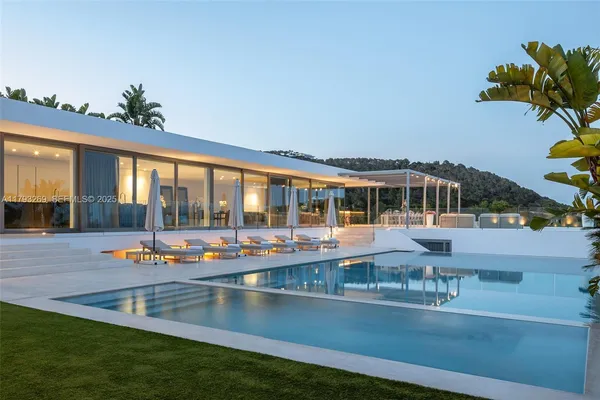 a view of a swimming pool with a lawn chairs and a floor to ceiling window