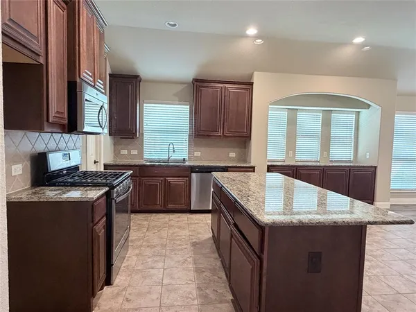a kitchen with stainless steel appliances granite countertop a stove a sink and a microwave