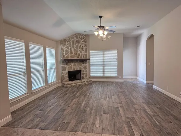 a view of empty room with a fireplace and wooden floor
