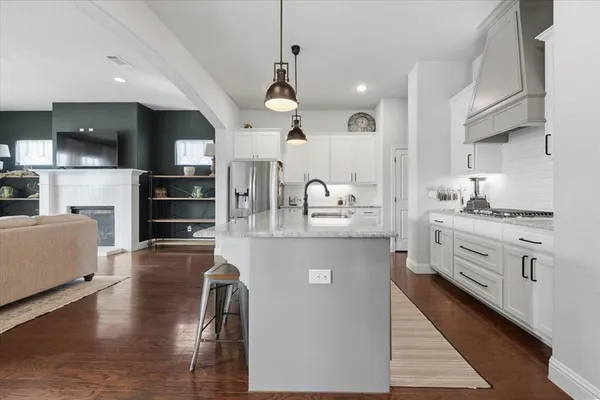 a kitchen with stainless steel appliances kitchen island granite countertop a stove a sink and a refrigerator