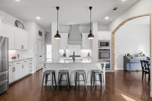 a large kitchen with white cabinets stainless steel appliances and wooden floor