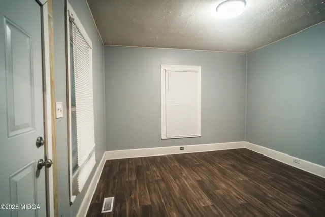 an empty room with wooden floor and window