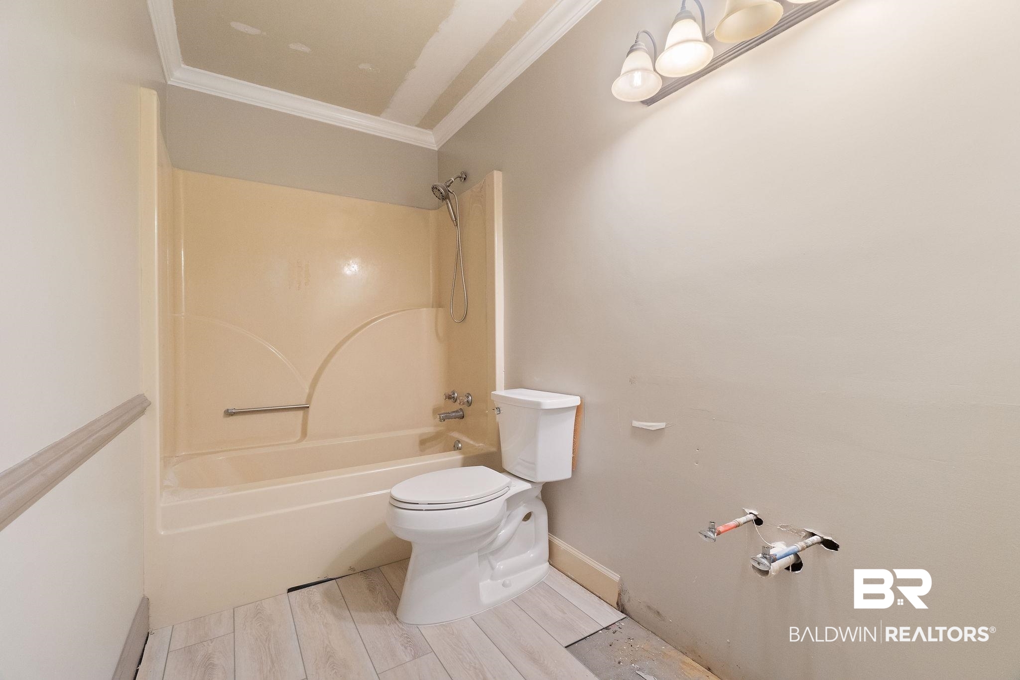 27300 C R Watson Road Robertsdale, AL 36567 - Photo 18 of 35 Bathroom featuring wood-type flooring, tub / shower combination, crown molding, and toilet