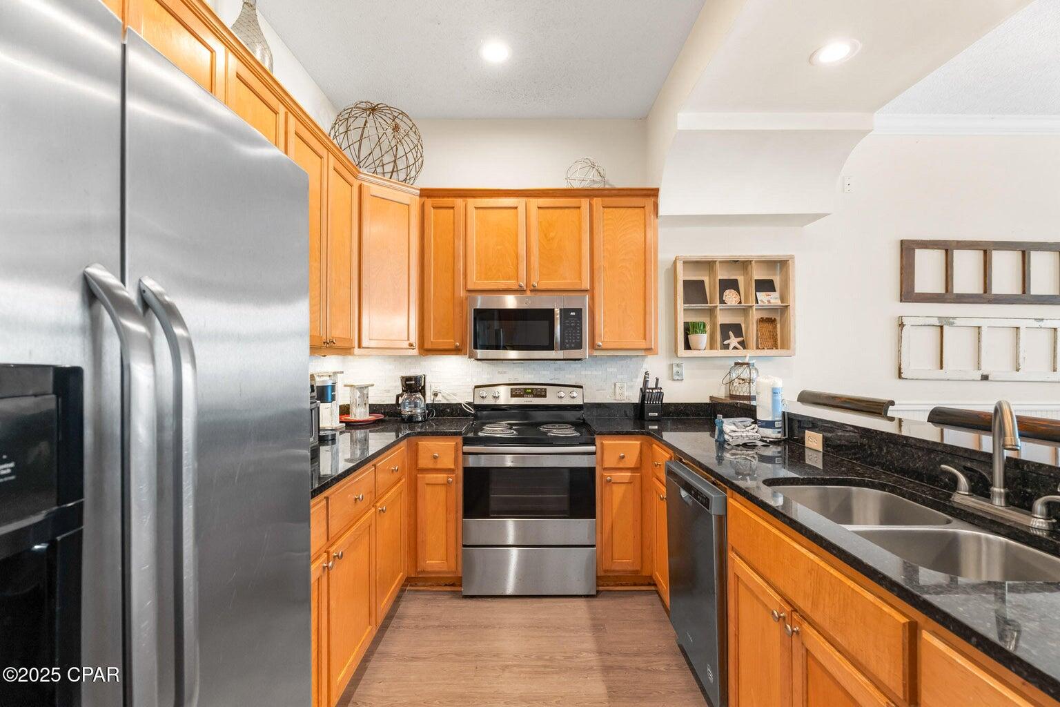 17657 Front Beach Road, Unit B Panama City Beach, FL 32413 - Photo 19 of 34 a kitchen with granite countertop a sink stainless steel appliances cabinets and a counter top space