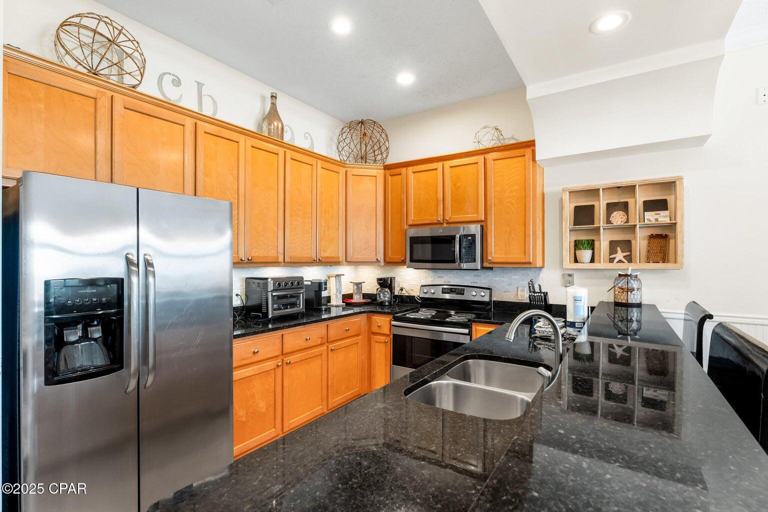 17657 Front Beach Road, Unit B Panama City Beach, FL 32413 - Photo 20 of 34 a kitchen with stainless steel appliances granite countertop a stove refrigerator and cabinets