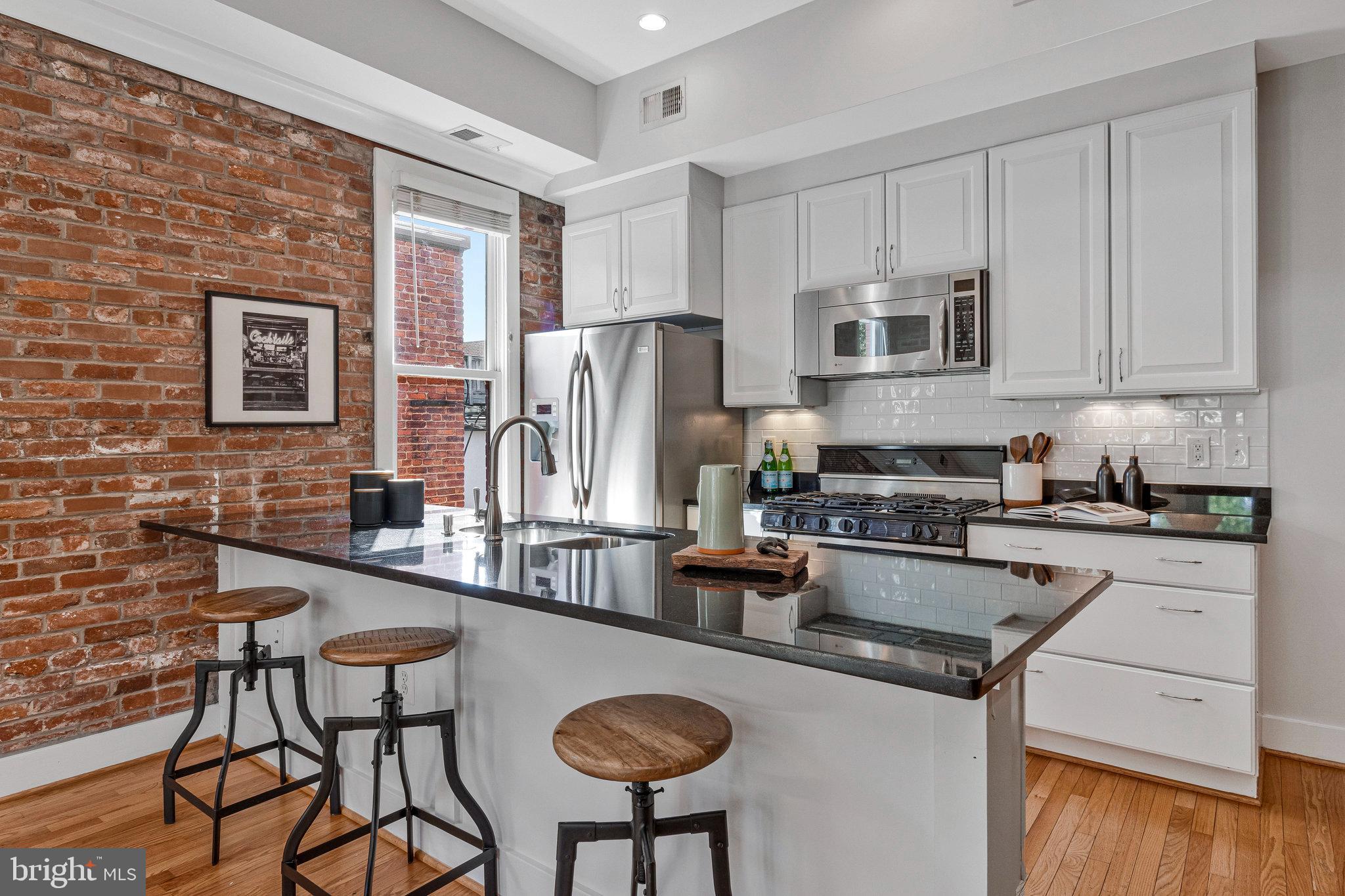 1312 Florida Avenue Northwest, Unit 3 Washington, DC 20009 - Photo 5 of 18 a kitchen with stainless steel appliances granite countertop a table chairs microwave and sink