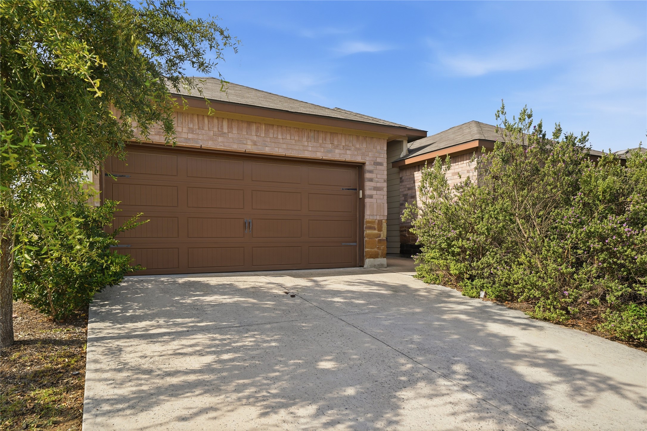 533 Jack Rabbit Lane, Unit A Buda, TX 78610 - Photo 6 of 34 A spacious driveway leads to a welcoming home, featuring a two-car garage and mature landscaping.