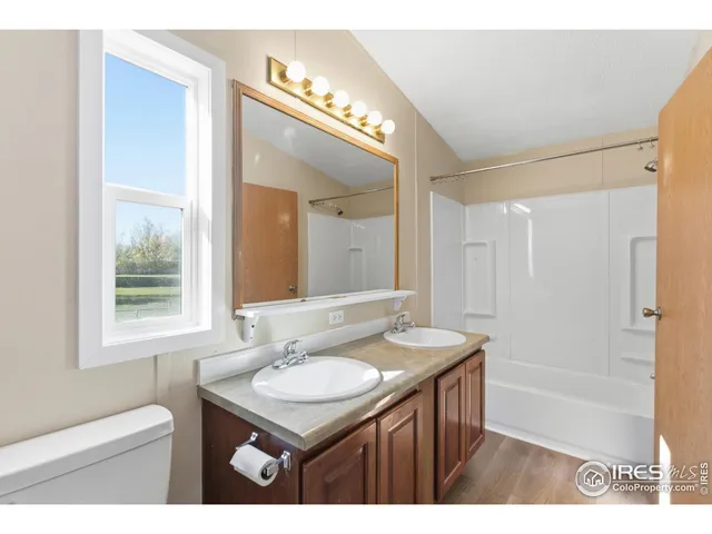a bathroom with a granite countertop sink a toilet a mirror and shower