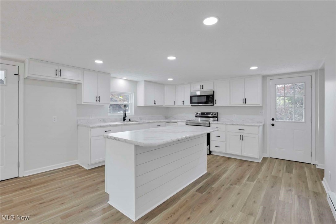 455 Back Run Road Philo, OH 43771 - Photo 11 of 44 Kitchen featuring stainless steel appliances, a sink, light wood-style floors, white cabinets, and a center island