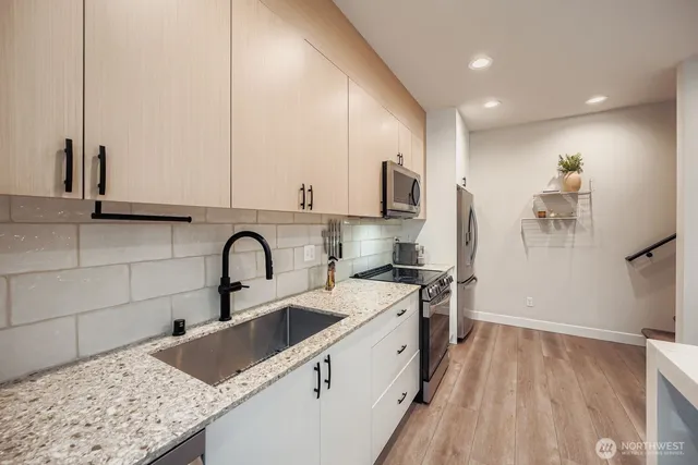 a kitchen with stainless steel appliances granite countertop a sink a stove and a wooden floors