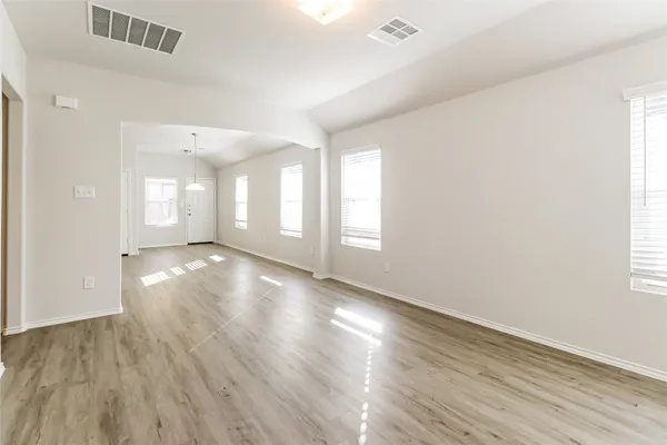 an empty room with wooden floor and windows