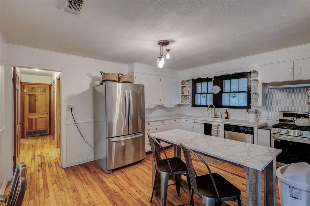 440 South Main Street Springtown, TX 76082 - Photo 9 of 33 a kitchen with stainless steel appliances granite countertop a refrigerator a stove a sink a dining table and chairs with wooden floor