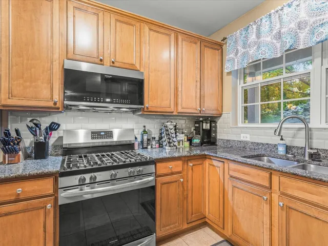 a kitchen with granite countertop cabinets stainless steel appliances a sink and window