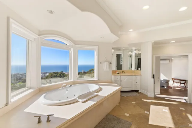 a bathroom with a tub a sink and a large mirror