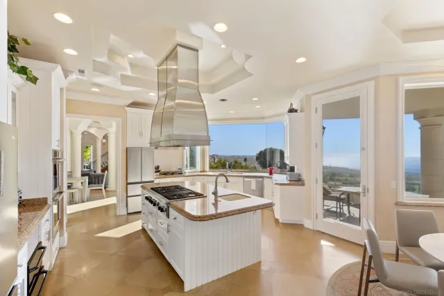 a large white kitchen with a large window and stainless steel appliances