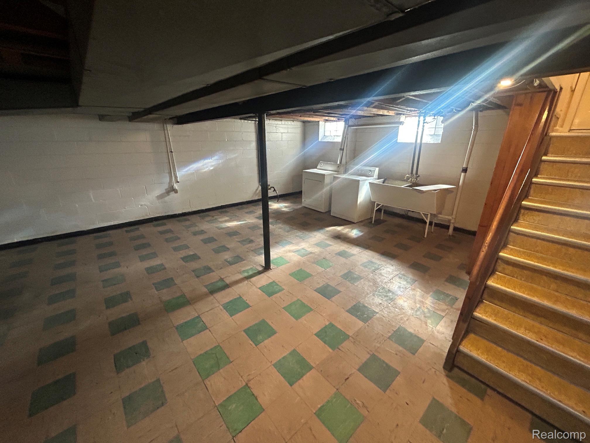21970 Moross Road Grosse Pointe, MI 48236 - Photo 17 of 21 Spacious utility area featuring patterned tile flooring, exposed ceiling joists, white block walls, and a wood staircase