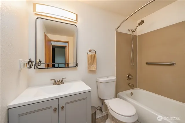 a bathroom with a toilet sink vanity tub and mirror