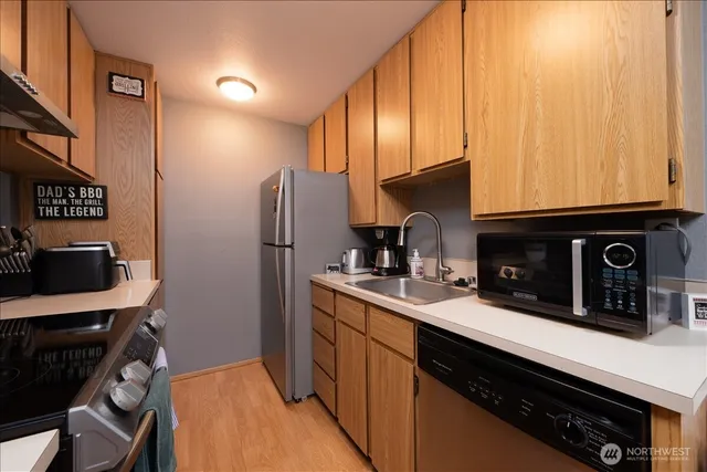 a kitchen with stainless steel appliances a sink a stove a refrigerator cabinets and a counter top space