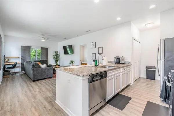 a kitchen with stainless steel appliances granite countertop a refrigerator a stove a sink a dining table and chairs with wooden floor