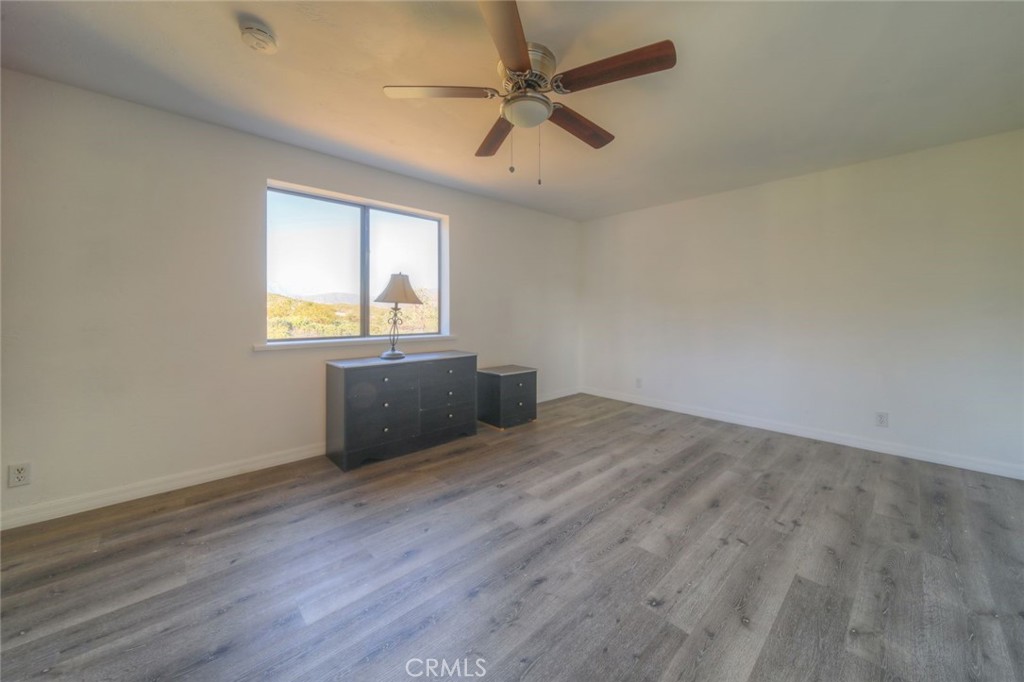 51201 Deer Mountain Way Anza, CA 92539 - Photo 27 of 65 an empty room with wooden floor ceiling fan and windows