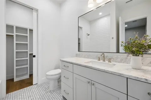a bathroom with a granite countertop sink a toilet and a mirror