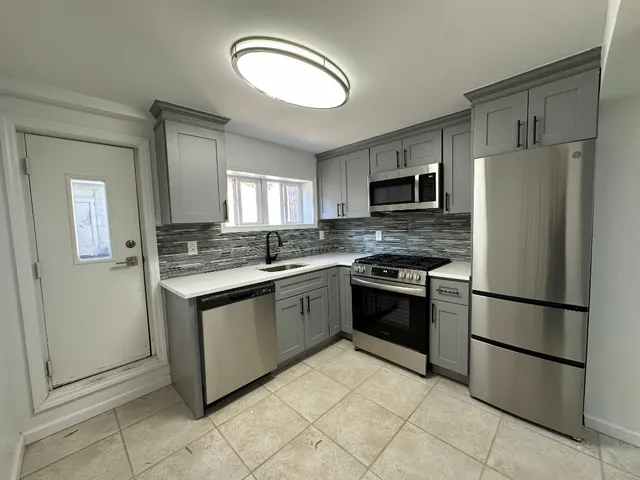 a kitchen with granite countertop a refrigerator and a stove top oven