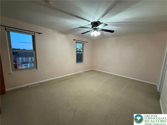 an empty room with windows and fan