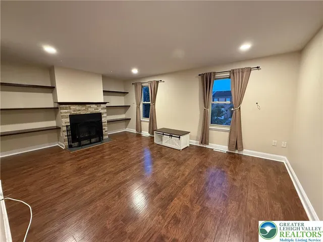 an empty room with wooden floor fireplace and windows