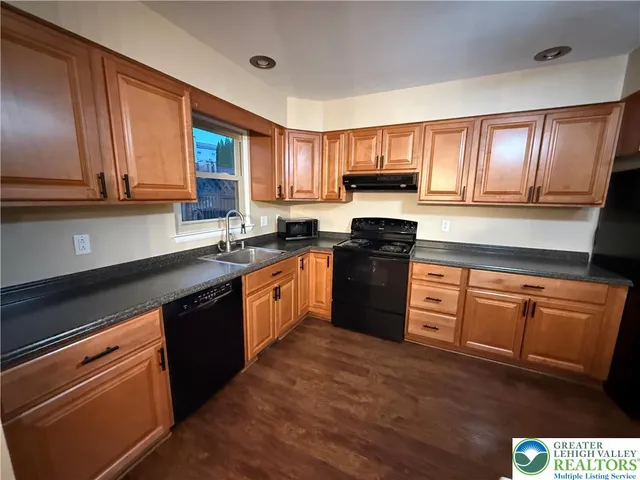 a kitchen with stainless steel appliances granite countertop wooden cabinets a stove top oven a sink and dishwasher with wooden floor