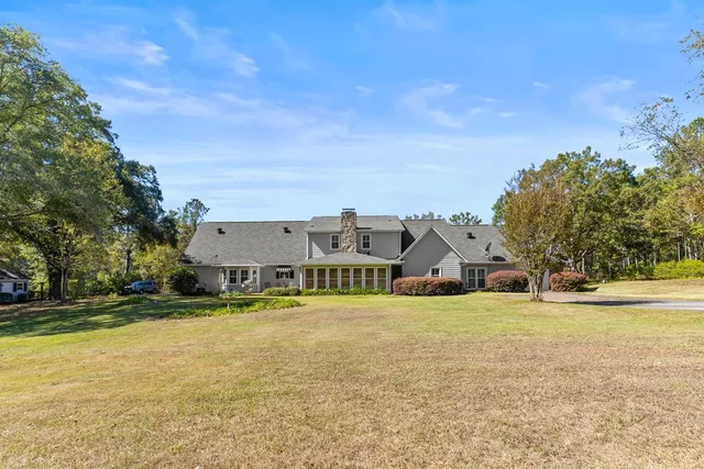a view of a house with a big yard and large trees