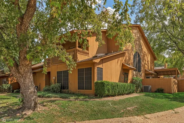 a view of a white house next to a yard with big trees