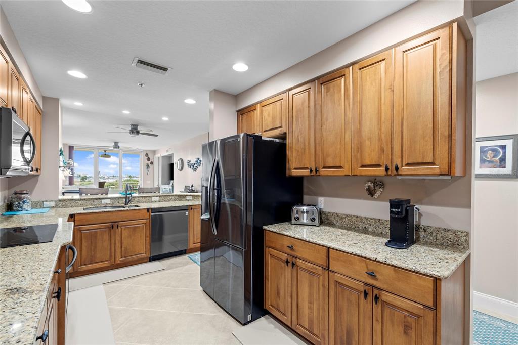 615 Riviera Dunes Way, Unit 204 Palmetto, FL 34221 - Photo 4 of 43 a kitchen with stainless steel appliances granite countertop a refrigerator a stove top oven and a sink with wooden floor