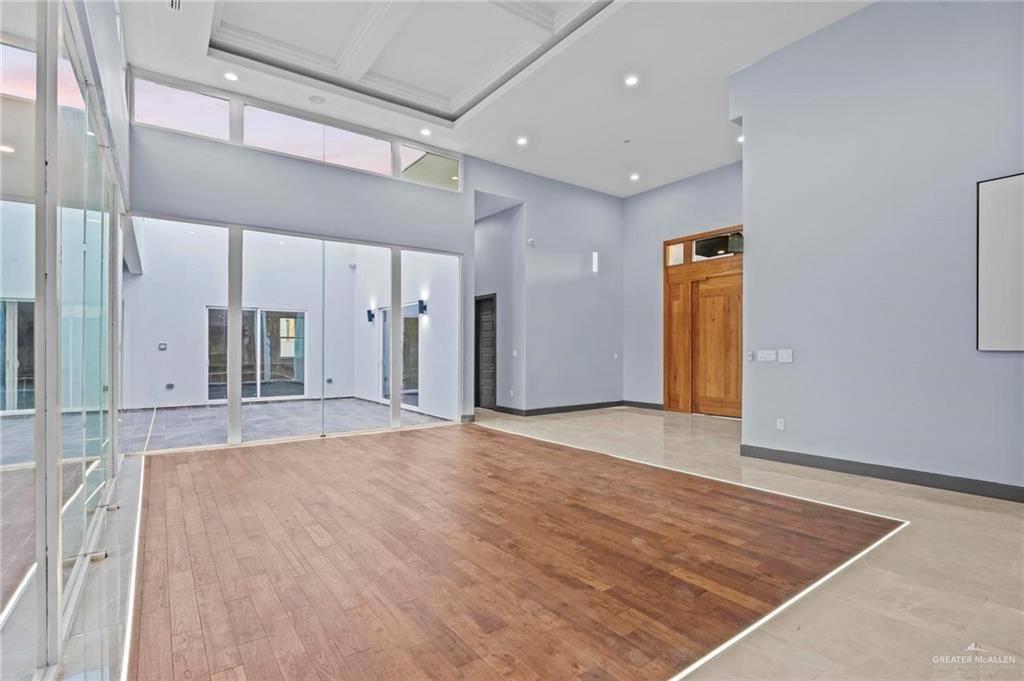 2321 Martha's Lane Mission, TX 78573 - Photo 7 of 36 Unfurnished living room featuring basketball hoop, a healthy amount of sunlight, a high ceiling, and light hardwood / wood-style flooring