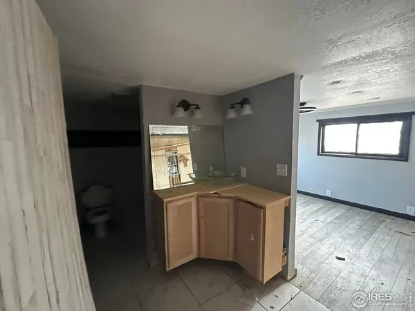 a bathroom with a granite countertop sink a toilet and a window