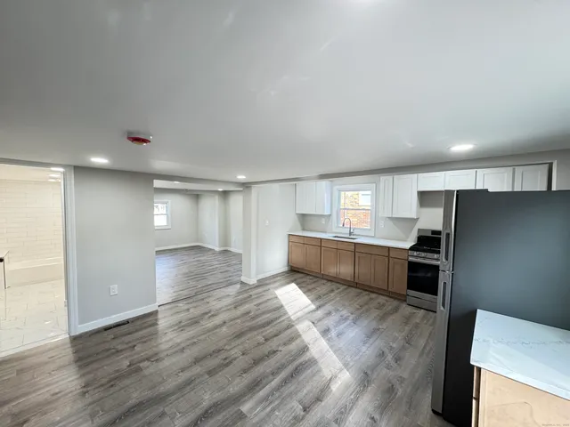 a view of kitchen with stainless steel appliances wooden floor and large window