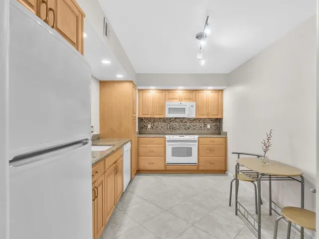a large white kitchen with a sink and dishwasher a stove top oven with wooden floor