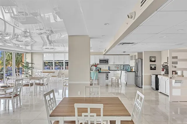 a kitchen with stainless steel appliances granite countertop a refrigerator a sink dishwasher a dining table and chairs with wooden floor